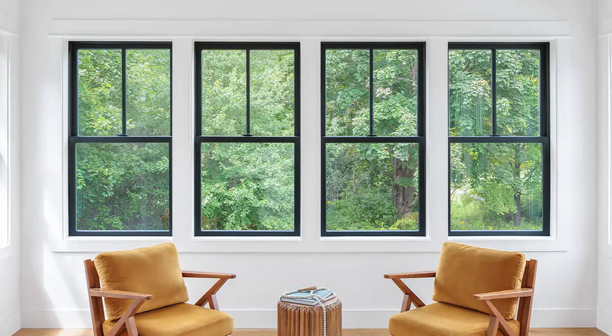 Living room with a row of black double-hung windows overlooking trees